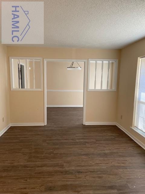 spare room featuring dark wood-type flooring and a textured ceiling