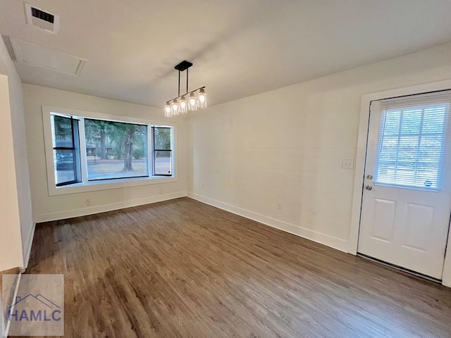 unfurnished dining area featuring plenty of natural light, wood finished floors, visible vents, and baseboards