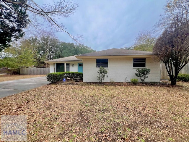 single story home with driveway, brick siding, and fence