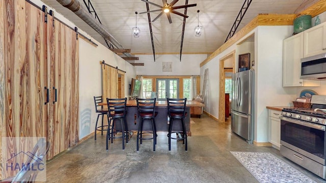 26 Cason Rd, Pembroke, GA 31321 - kitchen with appliances with stainless steel finishes, a barn door, concrete floors, white cabinetry, and a ceiling fan