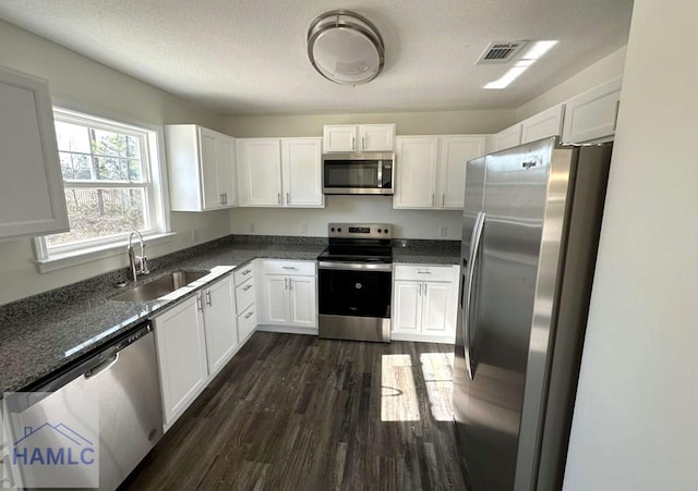 kitchen with appliances with stainless steel finishes, sink, dark wood-type flooring, and white cabinets