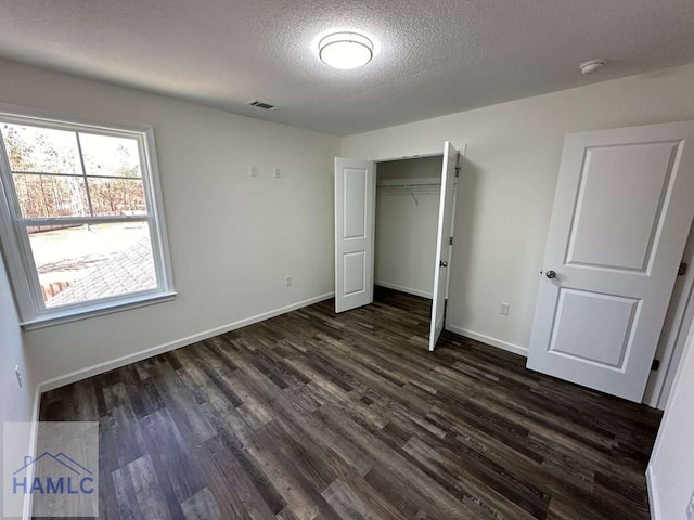 unfurnished bedroom featuring dark wood-type flooring, a closet, and a textured ceiling