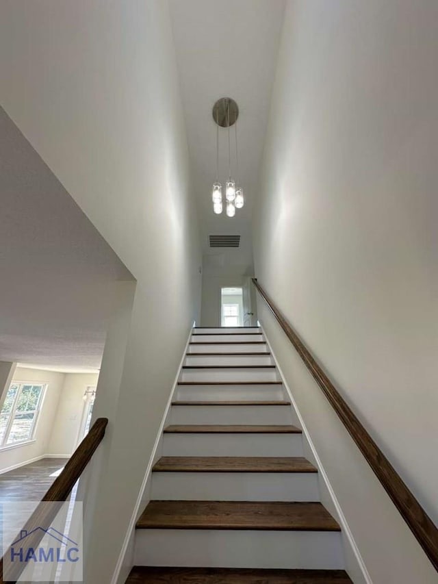 stairway with hardwood / wood-style flooring and a high ceiling