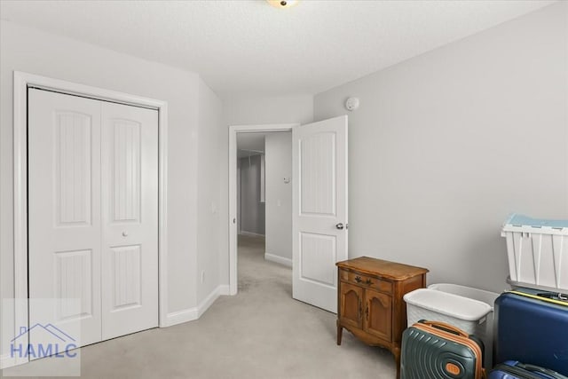 sitting room with baseboards, light carpet, and a textured ceiling