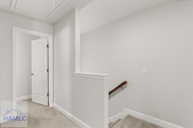 hallway with attic access, an upstairs landing, baseboards, and carpet floors