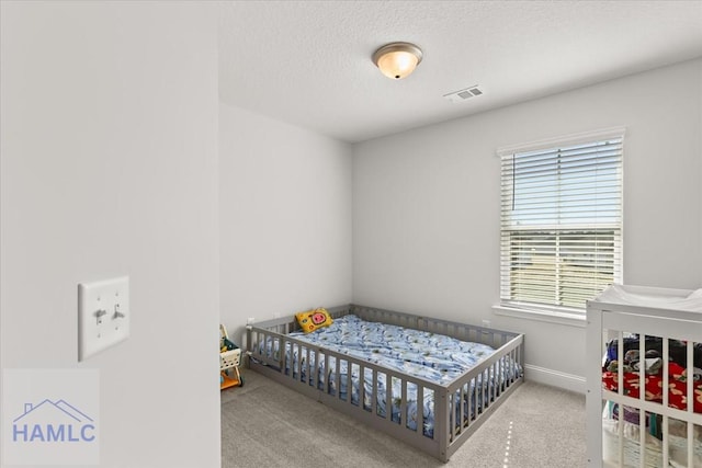 bedroom with baseboards, visible vents, a textured ceiling, and carpet