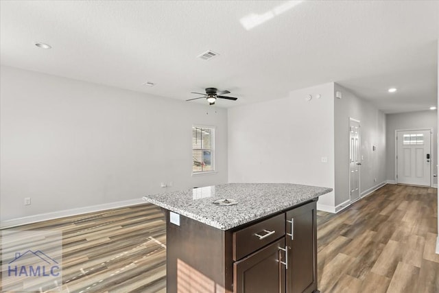 kitchen with baseboards, dark wood-type flooring, ceiling fan, and a kitchen island