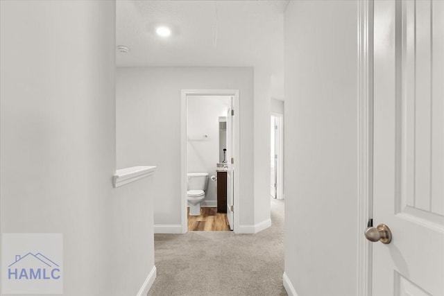 corridor featuring baseboards and carpet floors