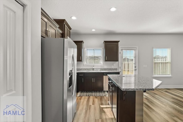 kitchen featuring a wealth of natural light, dark brown cabinets, appliances with stainless steel finishes, and a kitchen island