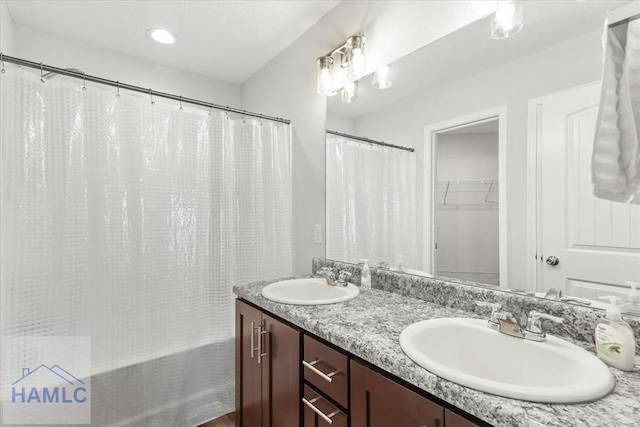 bathroom featuring double vanity, shower / tub combo with curtain, and a sink