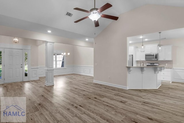 791 Stafford Dairy Rd SE, Ludowici, GA 31316 - unfurnished living room featuring decorative columns, ceiling fan, a wainscoted wall, light wood-style floors, and high vaulted ceiling