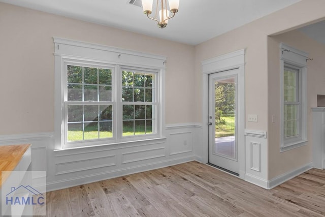 791 Stafford Dairy Rd SE, Ludowici, GA 31316 - doorway to outside featuring a wainscoted wall, a chandelier, plenty of natural light, and light wood finished floors