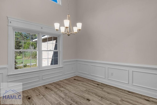 791 Stafford Dairy Rd SE, Ludowici, GA 31316 - unfurnished dining area with a chandelier, a wainscoted wall, plenty of natural light, light wood-style floors, and a decorative wall