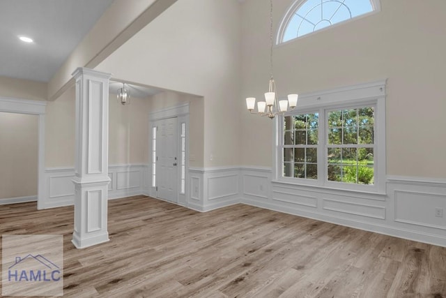 791 Stafford Dairy Rd SE, Ludowici, GA 31316 - entrance foyer featuring a chandelier, decorative columns, a wainscoted wall, light wood-type flooring, and a towering ceiling
