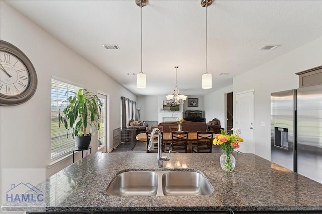 263NE Summer Hill Dr, Ludowici, GA 31316 - kitchen with a sink, stainless steel refrigerator with ice dispenser, pendant lighting, dark stone counters, and a chandelier