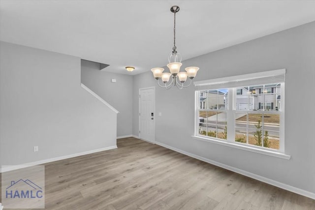 unfurnished dining area with a notable chandelier and light hardwood / wood-style flooring