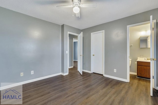 unfurnished bedroom with ensuite bathroom, ceiling fan, dark wood-type flooring, and sink