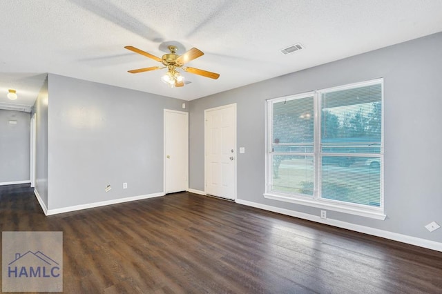 empty room with ceiling fan, dark wood-type flooring, and a textured ceiling