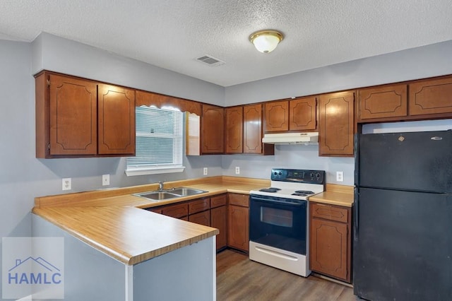 kitchen with dark wood-type flooring, black refrigerator, white electric range, sink, and a textured ceiling