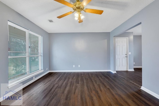 unfurnished room featuring ceiling fan, plenty of natural light, dark hardwood / wood-style floors, and a textured ceiling