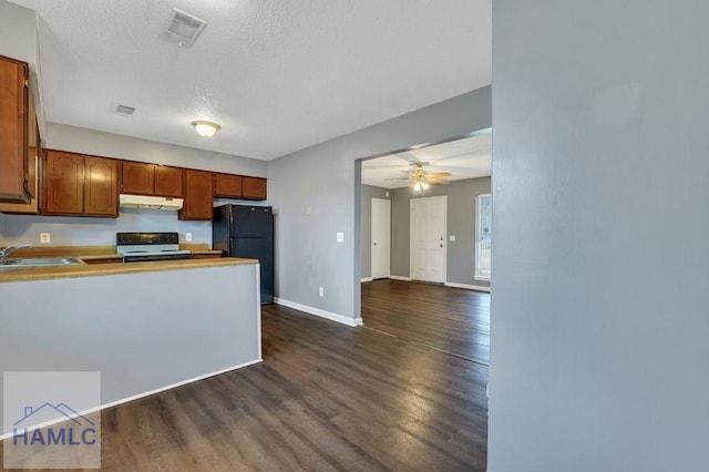 kitchen featuring dark hardwood / wood-style flooring, black fridge, a textured ceiling, sink, and white stove