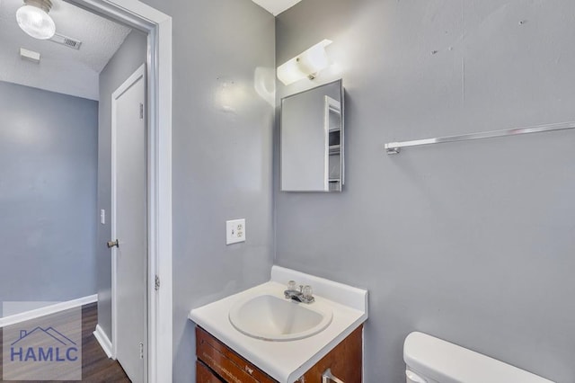 bathroom with vanity, a textured ceiling, and toilet