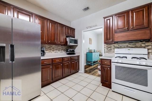 202 Red Bluff Cir, Rincon, GA 31326 - kitchen with stainless steel appliances, light countertops, decorative backsplash, light tile patterned floors, and a textured ceiling
