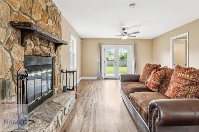 1019 Bacon Rd, Hinesville, GA 31313 - living room with wood finished floors, a ceiling fan, a fireplace, baseboards, and french doors