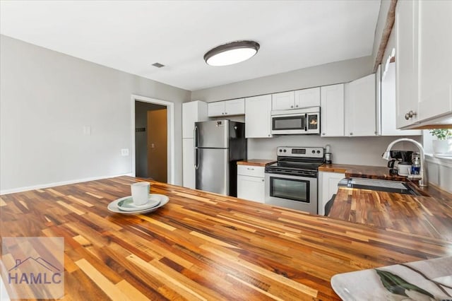 1019 Bacon Rd, Hinesville, GA 31313 - kitchen featuring butcher block countertops, stainless steel appliances, a sink, and white cabinetry