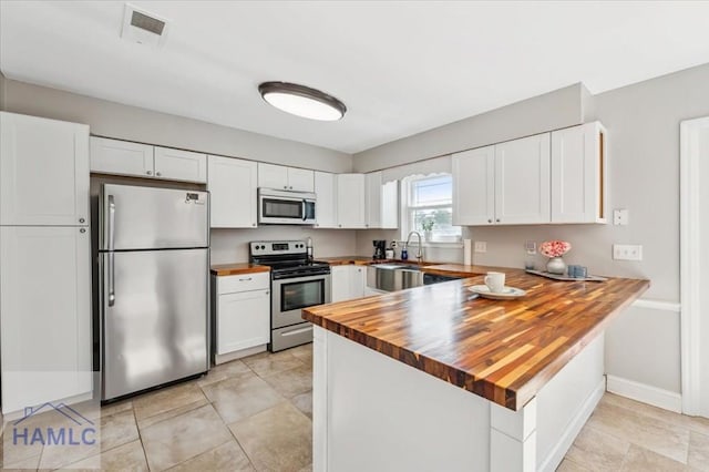 1019 Bacon Rd, Hinesville, GA 31313 - kitchen featuring appliances with stainless steel finishes, wood counters, a peninsula, white cabinetry, and a sink