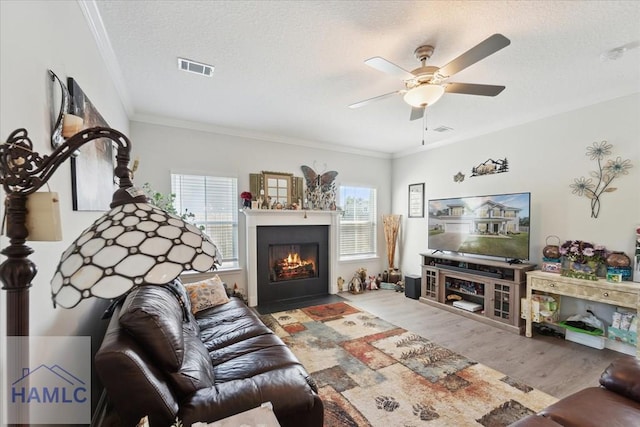 living area with a textured ceiling, ceiling fan, wood finished floors, and a healthy amount of sunlight