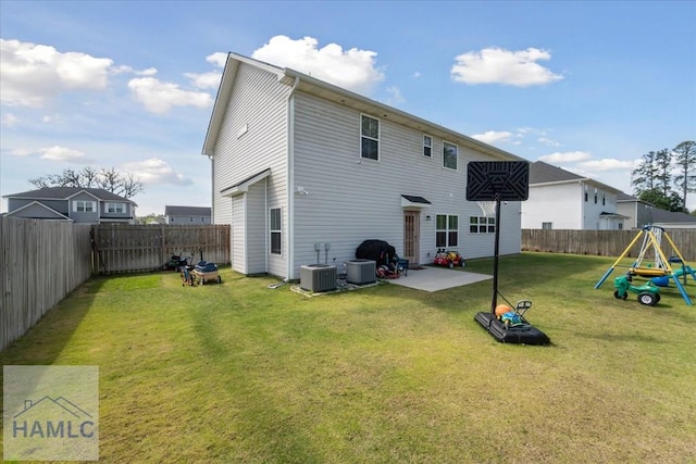 back of house featuring central AC, a fenced backyard, a patio area, a playground, and a lawn