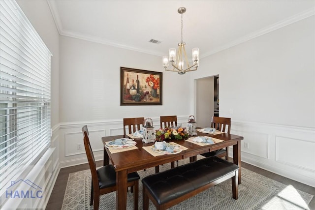 dining area featuring wood finished floors, a decorative wall, a chandelier, and visible vents