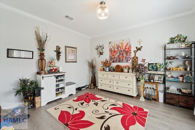 sitting room featuring visible vents, ornamental molding, and wood finished floors