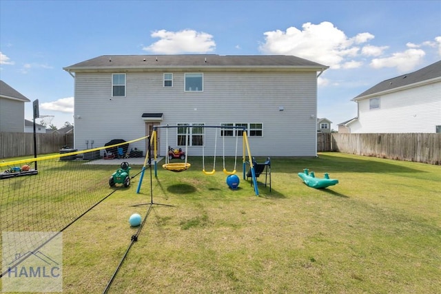 rear view of house featuring a yard, fence, and a playground