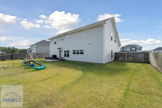 rear view of house featuring a playground, a yard, and a fenced backyard