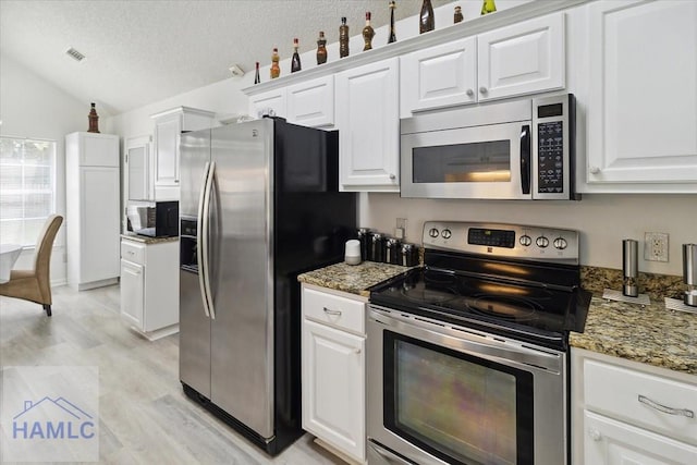 kitchen with stone counters, white cabinetry, stainless steel appliances, light hardwood / wood-style floors, and vaulted ceiling