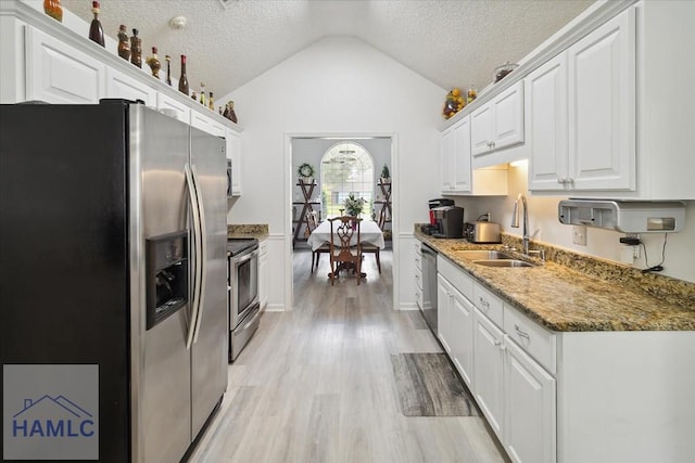 kitchen with white cabinetry, sink, stainless steel appliances, a textured ceiling, and lofted ceiling