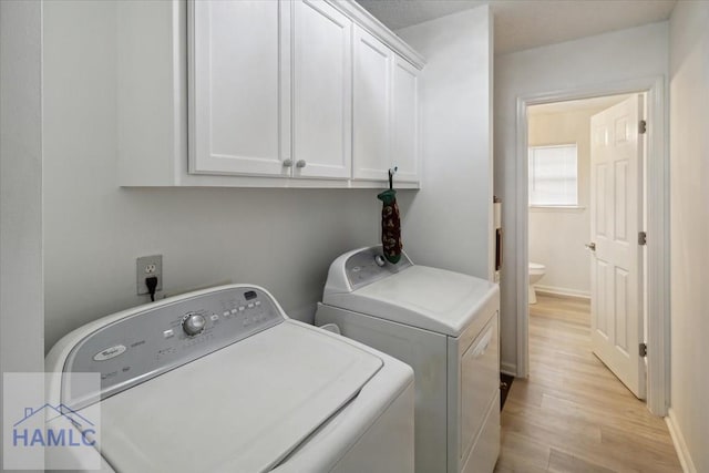 laundry room with washer and clothes dryer, cabinets, and light wood-type flooring