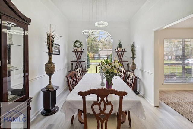 dining space featuring light wood-type flooring, ornamental molding, and an inviting chandelier