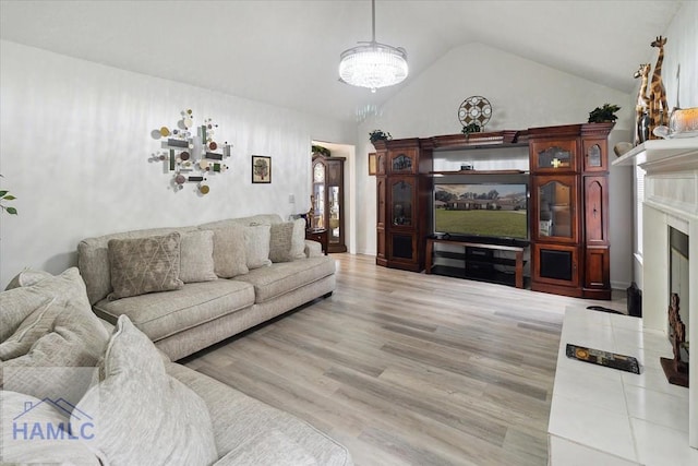 living room with a premium fireplace, light hardwood / wood-style flooring, and lofted ceiling