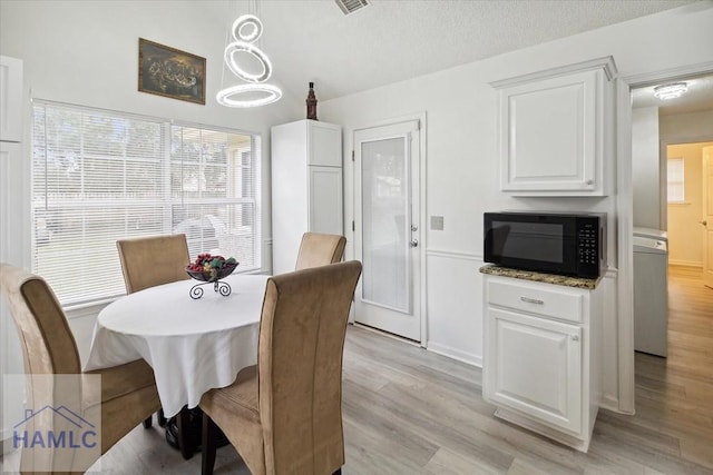 dining space with a textured ceiling and light wood-type flooring