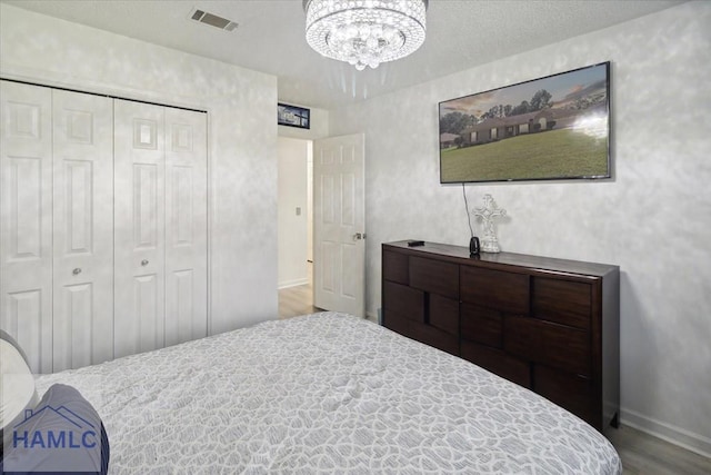 bedroom with hardwood / wood-style floors, a closet, and a notable chandelier