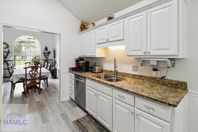 kitchen with dishwasher, white cabinetry, sink, and vaulted ceiling