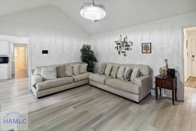 living room featuring light wood-type flooring, high vaulted ceiling, and an inviting chandelier