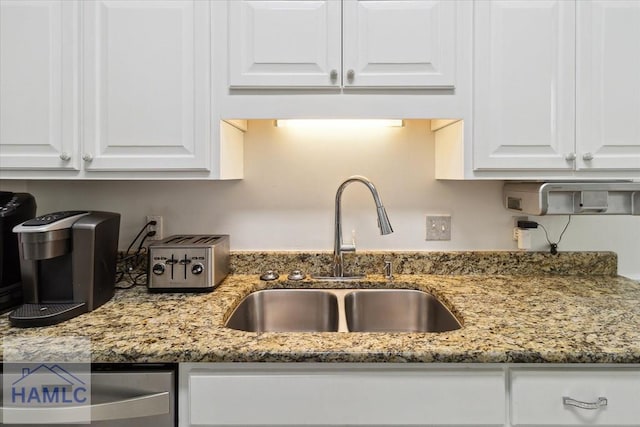 kitchen featuring light stone counters, sink, and white cabinets