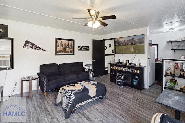 living room with bar, a textured ceiling, dark hardwood / wood-style flooring, and ceiling fan