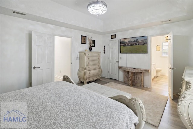 bedroom with ensuite bath and light wood-type flooring