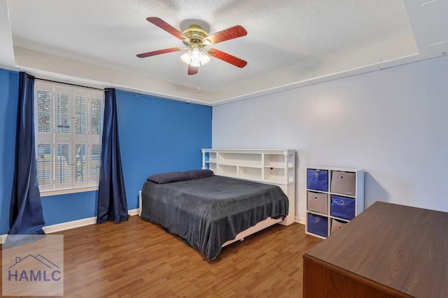 bedroom featuring hardwood / wood-style flooring, a textured ceiling, and ceiling fan