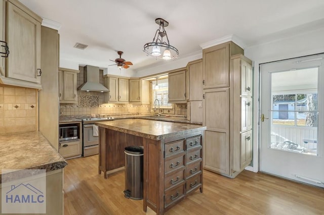 kitchen with wall chimney exhaust hood, stainless steel range oven, hanging light fixtures, light hardwood / wood-style flooring, and a kitchen island